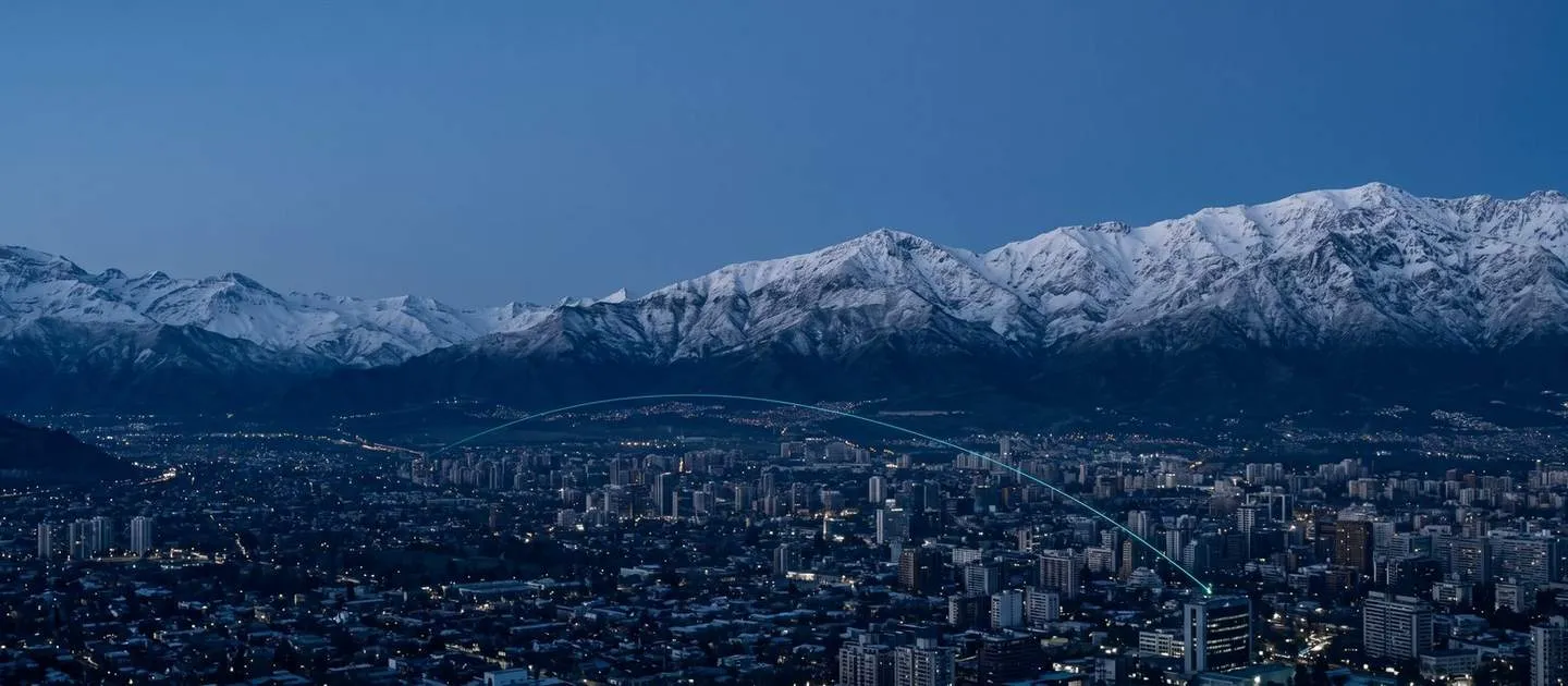 Ciudad al pie de una cordillera nevada al anochecer